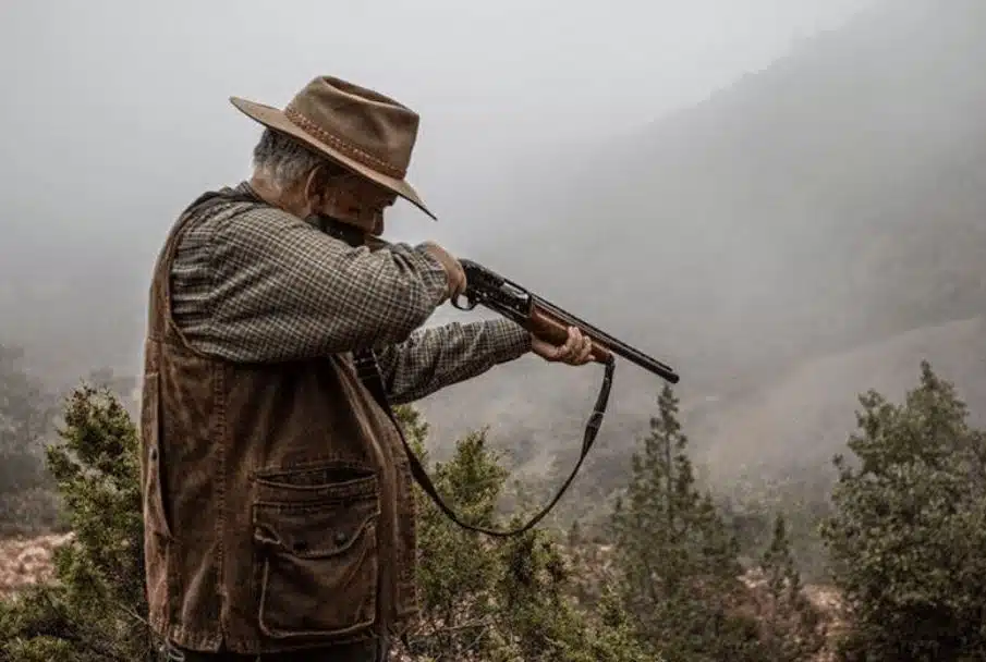 Hunter aiming a shotgun in a misty field